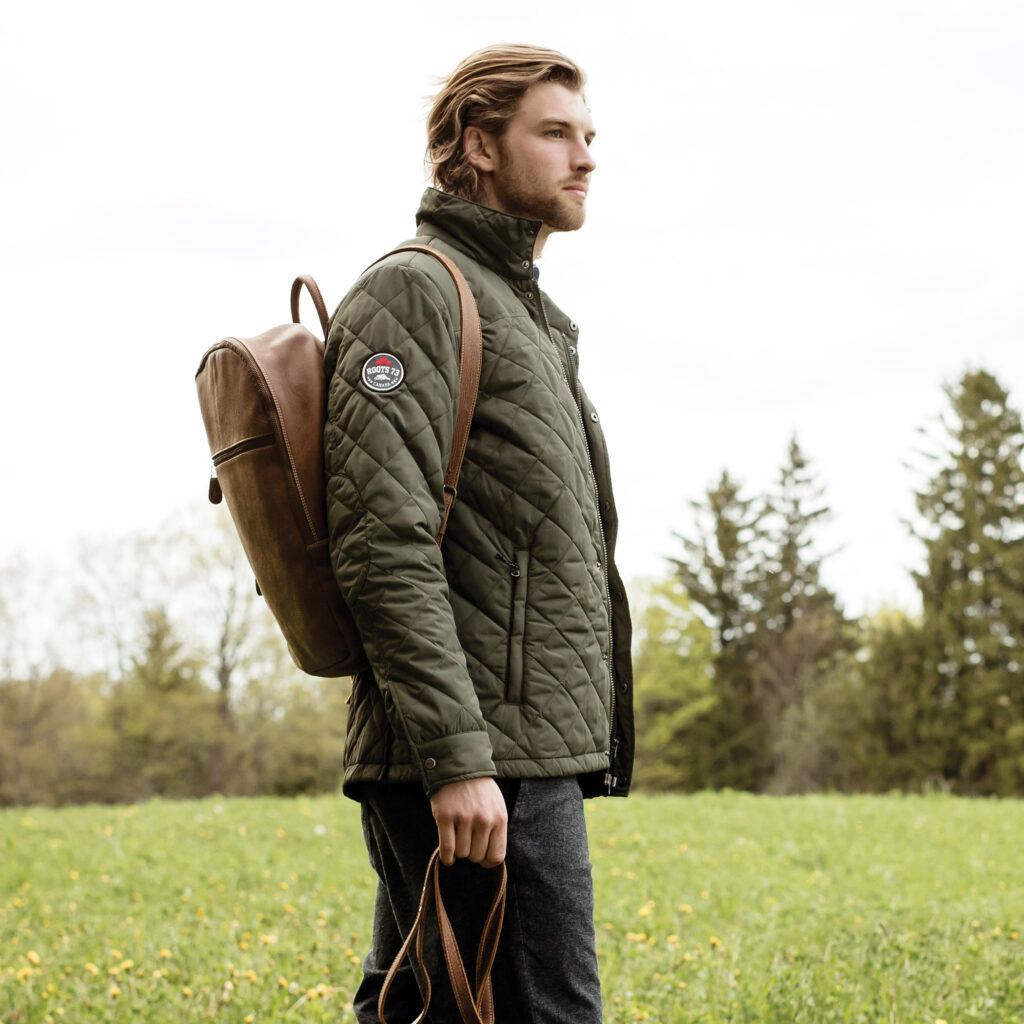 Man in a field with a custom jacket and leather bag